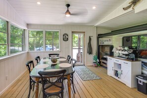 Un comedor con mesa y sillas de madera, una cocina con cafetera y vistas al exterior.