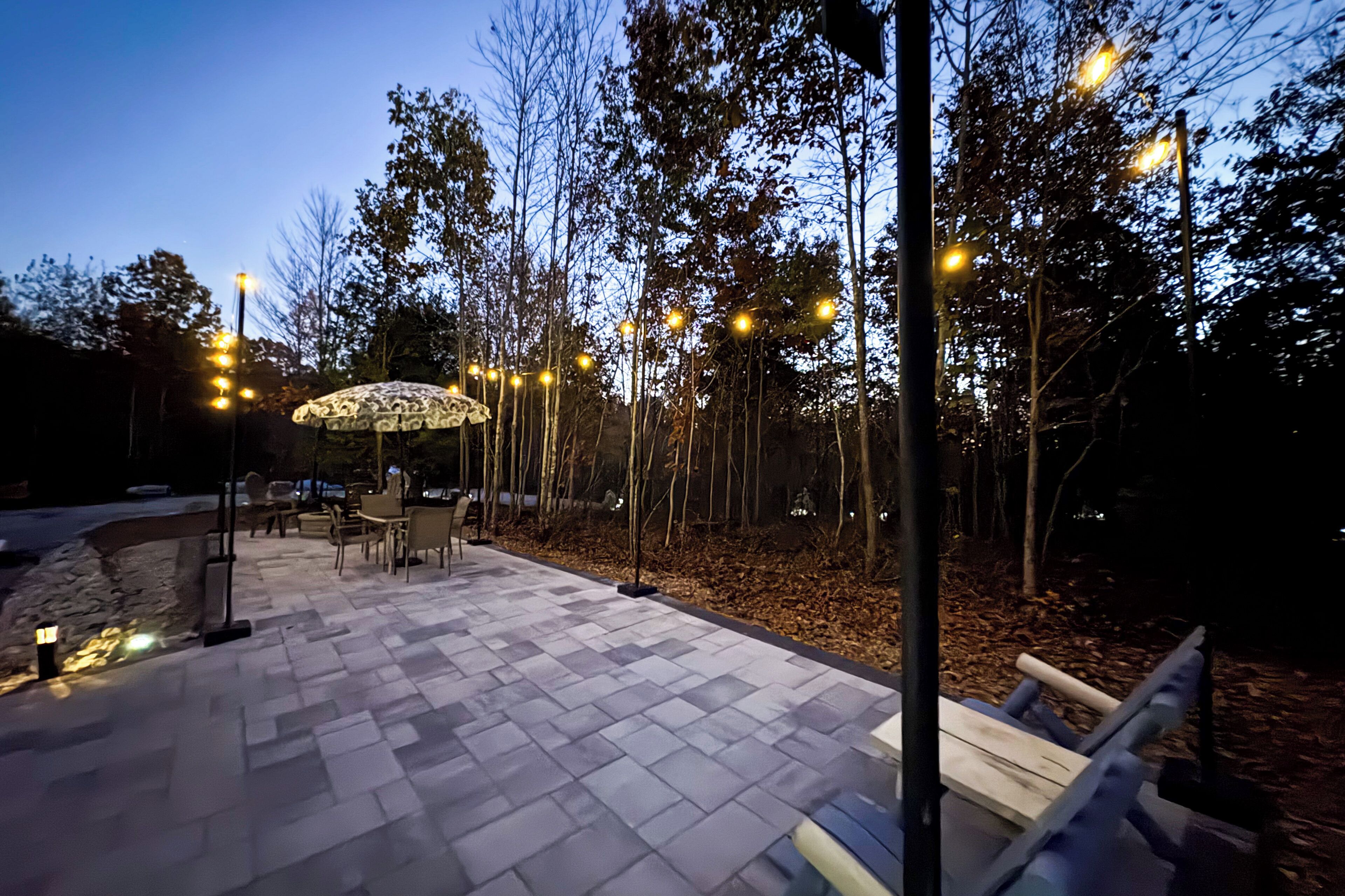 An outdoor patio area with a patterned floor, outdoor seating, and trees.