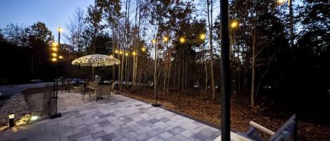 An outdoor patio area with a patterned floor, outdoor seating, and trees.