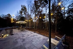 Un patio al aire libre con suelo estampado, mobiliario exterior y árboles.