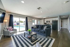 Ein modernes Wohnzimmer mit Sofa, Couchtisch und Blick auf einen Pool.