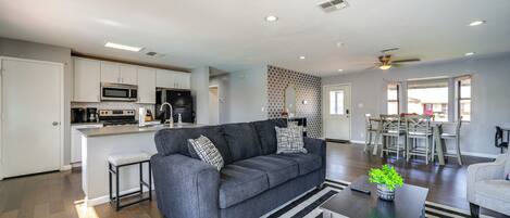 A modern kitchen with white cabinets, a microwave, and a dining area with a table and chairs.