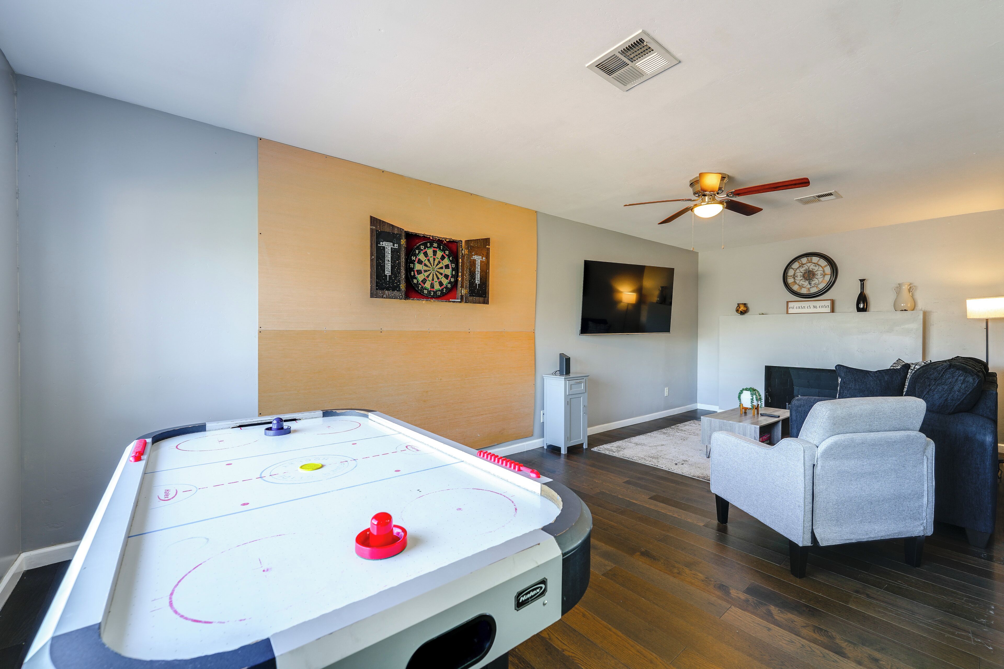 A living room with a pool table, a ceiling fan, a flat-screen TV, and a fireplace.
