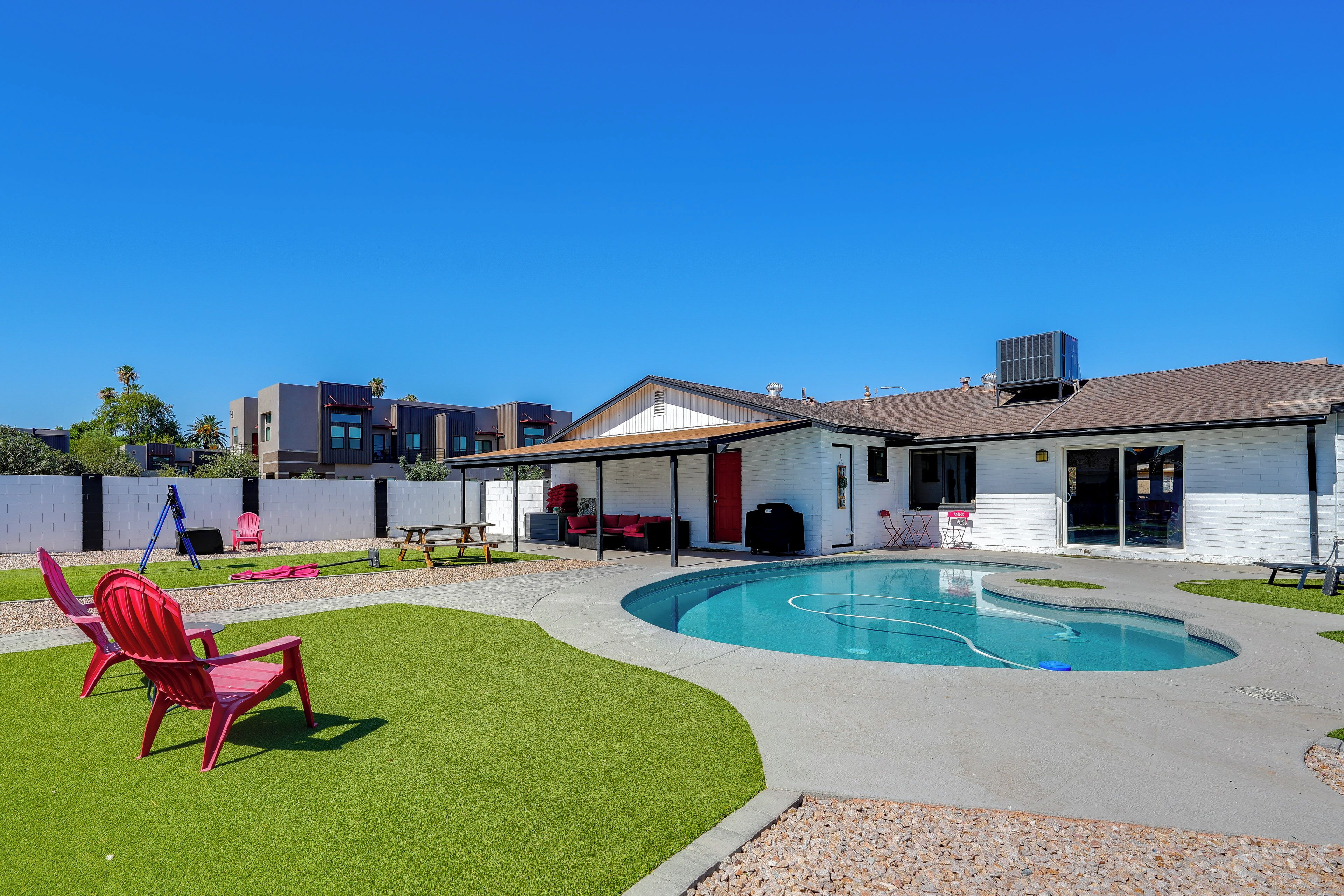 Uma casa moderna com piscina, um alpendre coberto e um gramado bem cuidado.