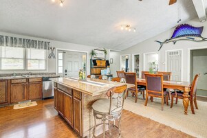 A spacious kitchen with wooden cabinets, a stainless steel dishwasher, and a large island with bar stools.