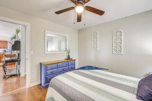 Un dormitorio con cama, cómoda, ventilador de techo y ventana con celosía decorativa.