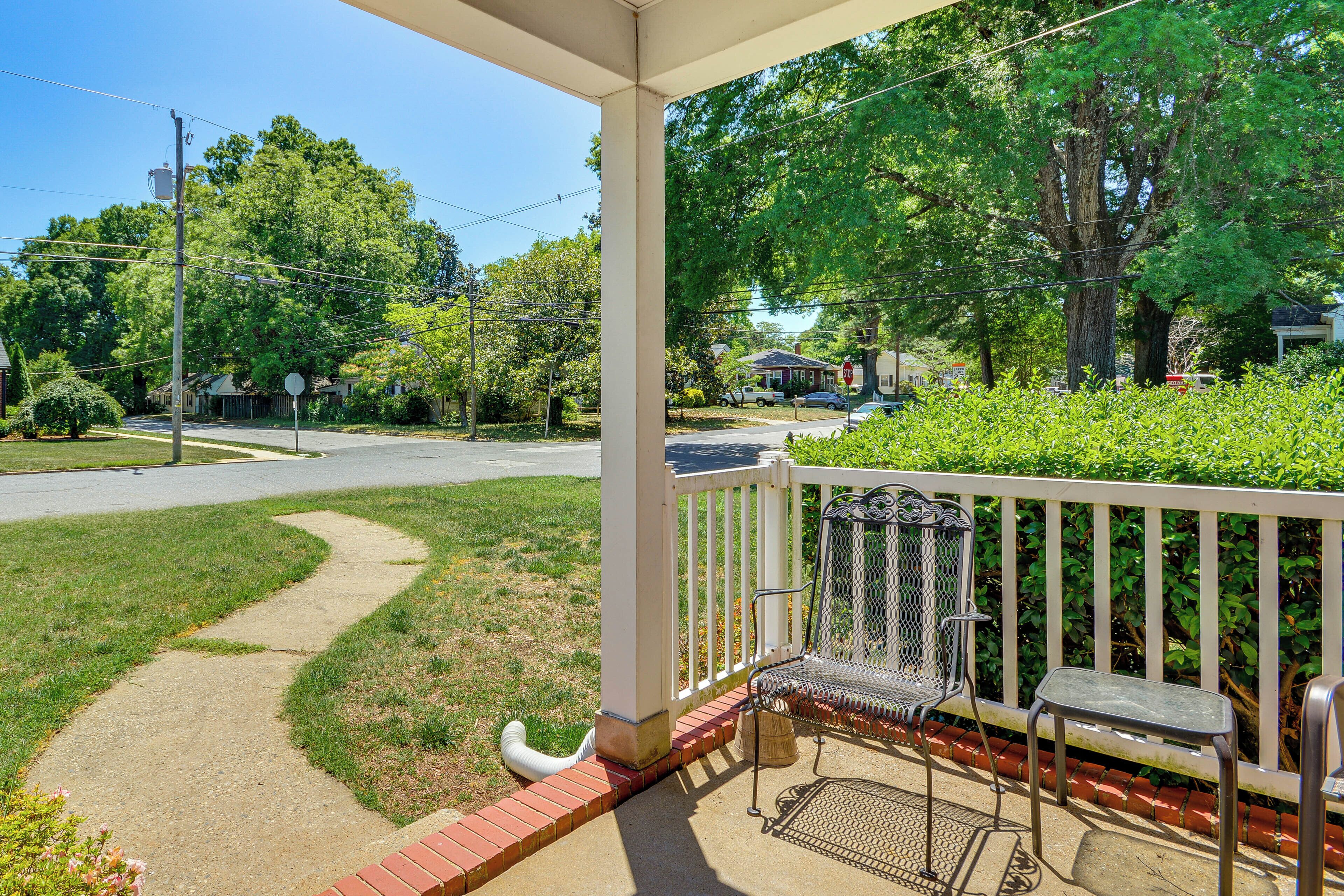 A covered porch with a metal bench and a stop sign in the background.