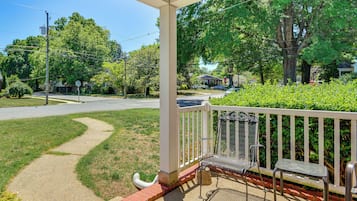 A covered porch with a metal bench and a stop sign in the background.