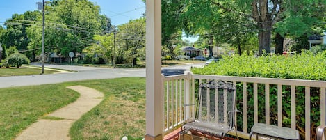 A covered porch with a metal bench and a stop sign in the background.