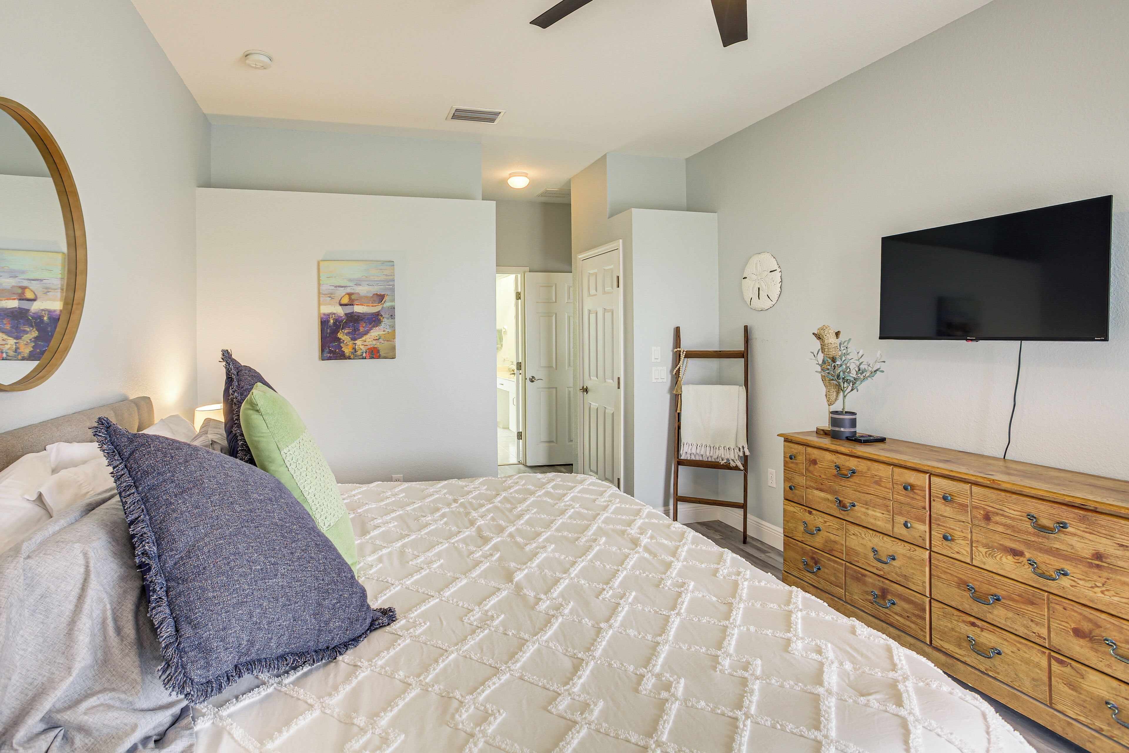 A bedroom with a bed, dresser, and a flat-screen TV on the wall.