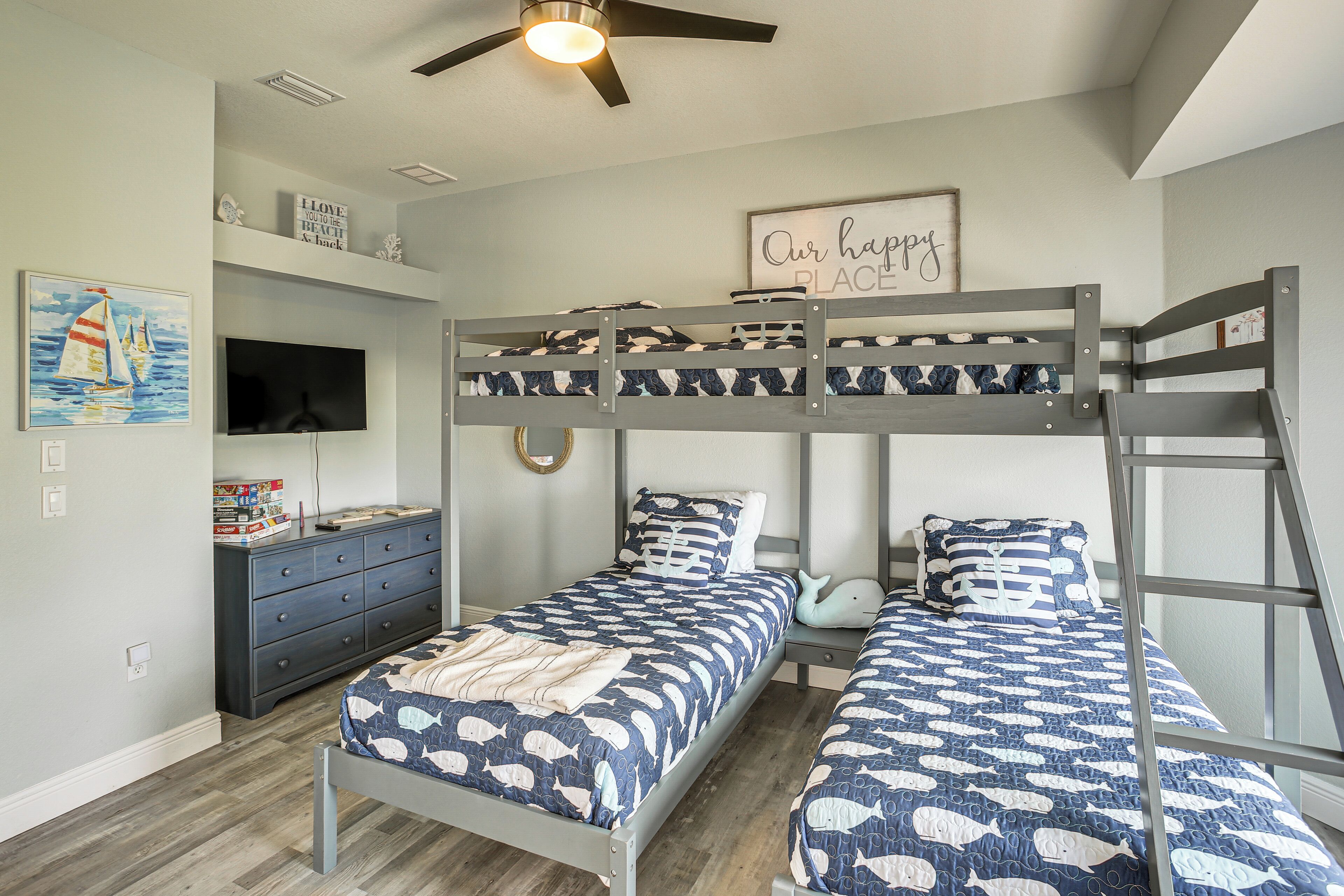 Un dormitorio con literas, un aparador, un televisor y una pared con un letrero que dice 'Our happy place'.