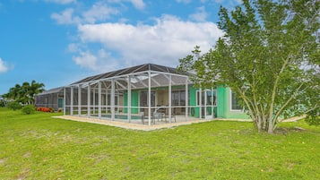 A covered outdoor area with a glass enclosure, a green wall, and a tree.