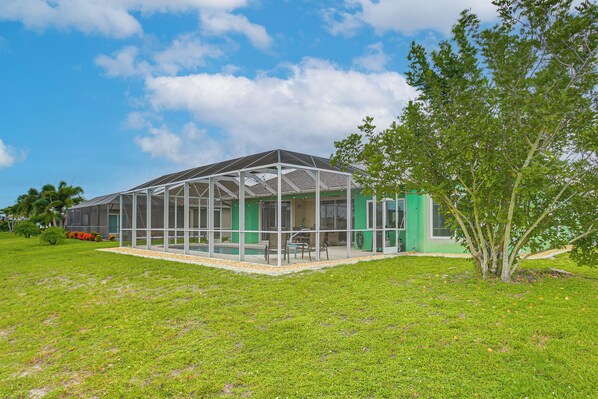 A covered outdoor area with a glass enclosure, a green wall, and a tree.