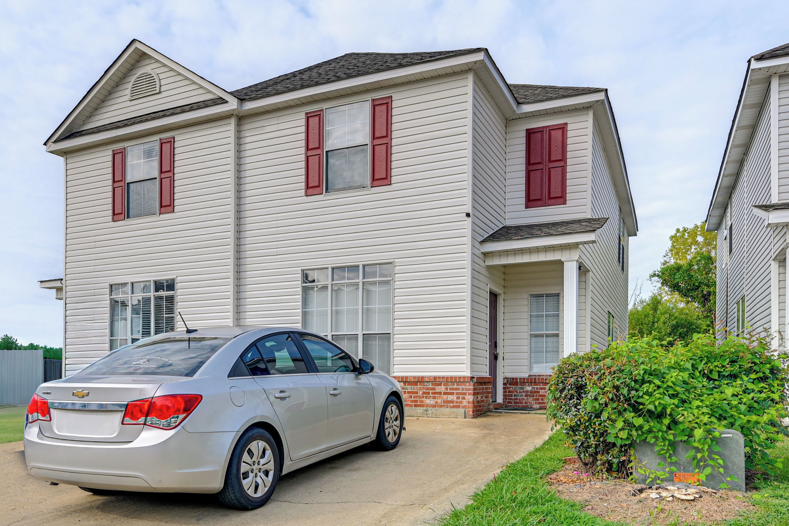 A two-story residential building with a car parked in front.