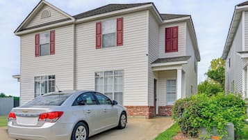 A two-story residential building with a car parked in front.
