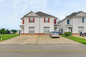 A two-story residential building with a driveway and a parked car.