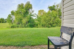 A bench outside a building with a grassy yard and trees in the background.