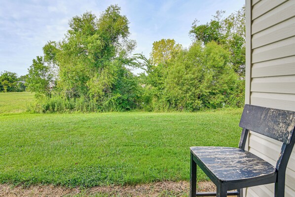 A bench outside a building with a grassy yard and trees in the background.