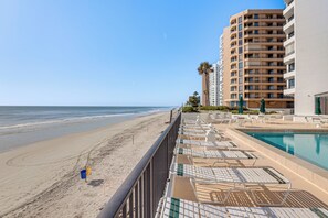 Ein Hotel am Strand mit Pool, Liegestühlen und Blick auf das Meer.