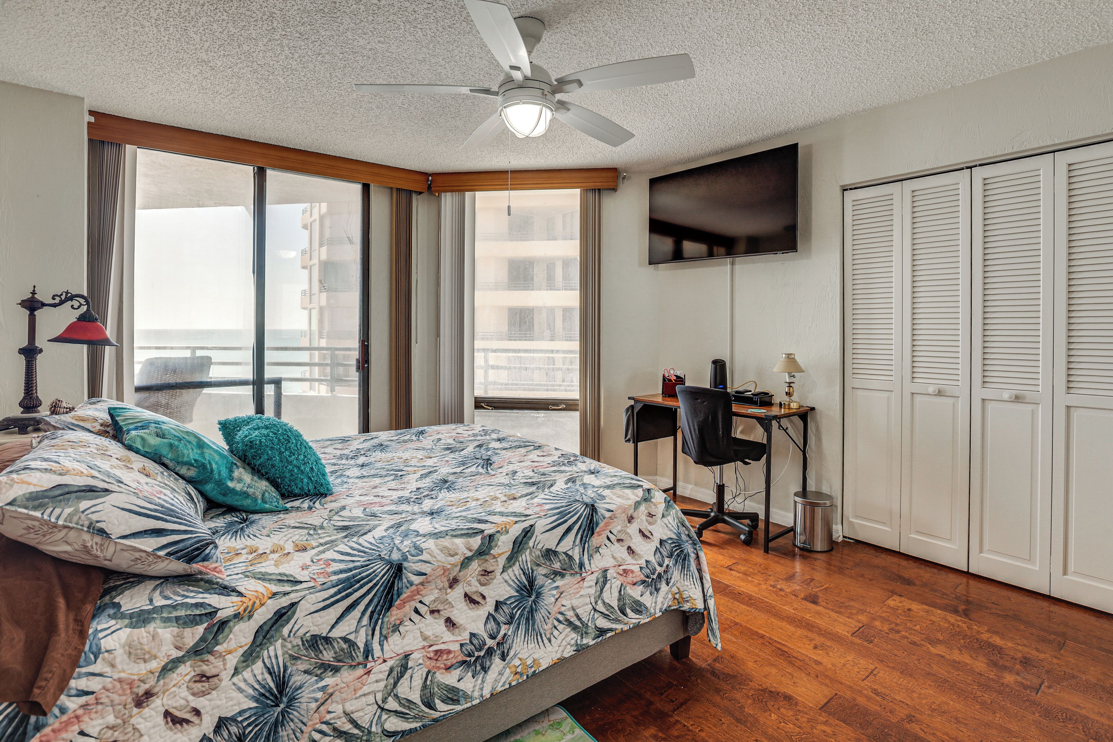 Ein Schlafzimmer mit Bett, Schreibtisch, Stuhl, Fernseher und Kleiderschrank.