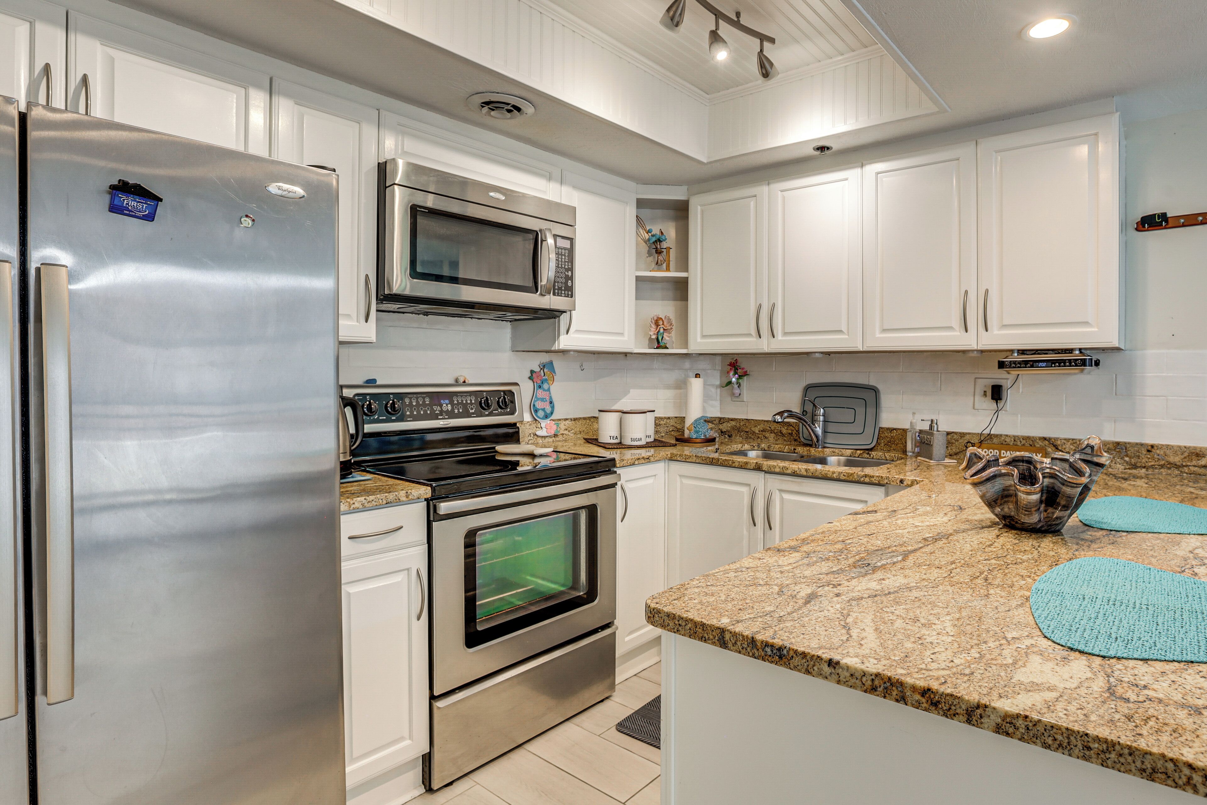 A modern kitchen with stainless steel appliances, white cabinetry, and granite countertops.