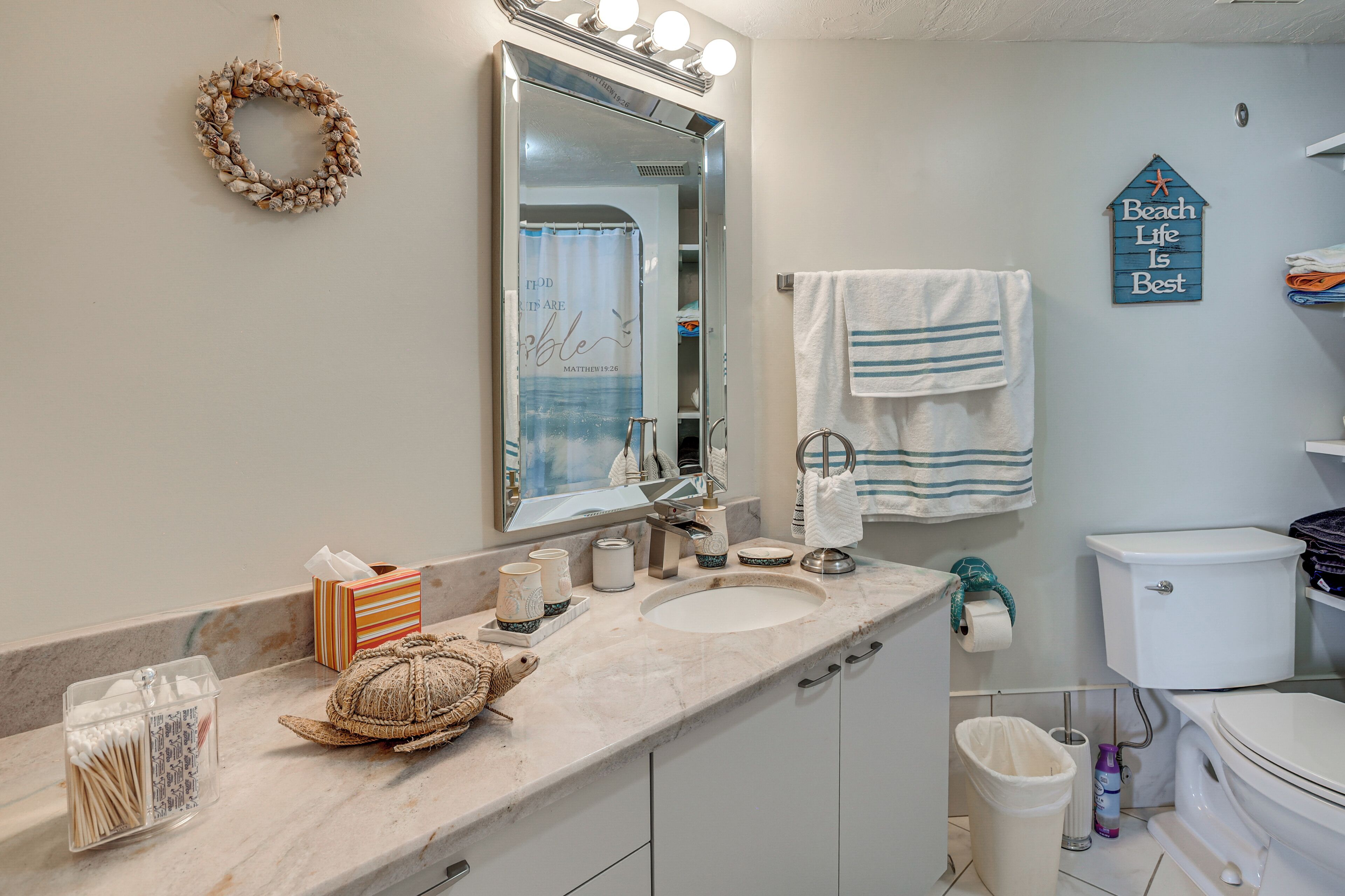 A bathroom with a vanity, sink, mirror, towel rack, and a toilet.