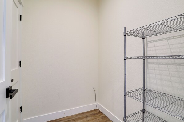 A corner of a room with a white wall, a wooden floor, and a metal shelving unit against the wall.