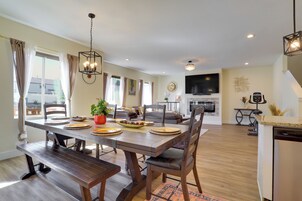 Un comedor con una mesa de madera preparada para cuatro, un sofá y un televisor al fondo.