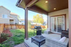 Un patio techado con una parrilla, mobiliario exterior y vistas al jardín.