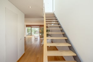 Ein modernes Interieur mit einer Holztreppe, einem Essbereich und Blick ins Freie.