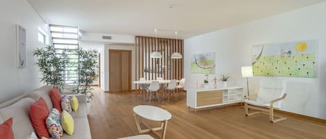 Una sala moderna con un sofá, un comedor y un ventanal grande.