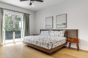 Un dormitorio con una cama, una mesita de noche, un ventilador de techo y dos cuadros en la pared.