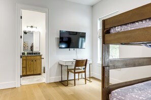 A bedroom with a bunk bed, a desk with a chair, a television, and a bathroom with a mirror and sink. - Pool & Lake Access! Dual Homes on Canyon Lake (Canyon Lake)