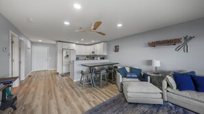 Una cocina moderna con armarios blancos, una isla central y un ventilador de techo.
