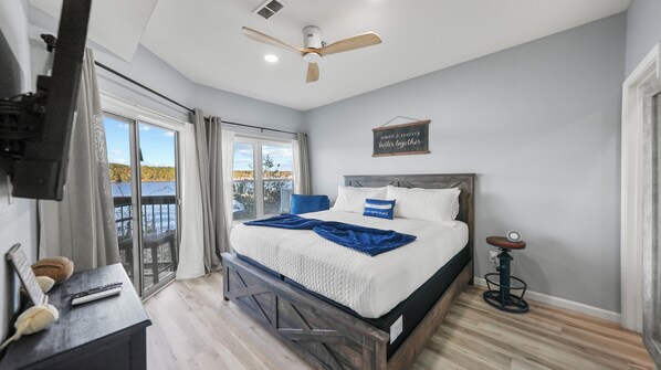 Un dormitorio con cama, ventilador de techo, mesita de noche y vista al exterior.