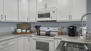 A kitchen with white cabinets, a microwave, an oven, a coffee maker, and a sign that reads 'Lake Ozark Oasis Coffee Bar'. - Waterfront Oasis with Theater, Game Room, 2 King Suites, 2 Pools, Boat Slip (Osage Beach)