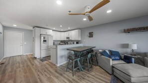 A modern kitchen with white cabinets, a wooden dining table, and a ceiling fan. - Waterfront Oasis with Theater, Game Room, 2 King Suites, 2 Pools, Boat Slip (Osage Beach)