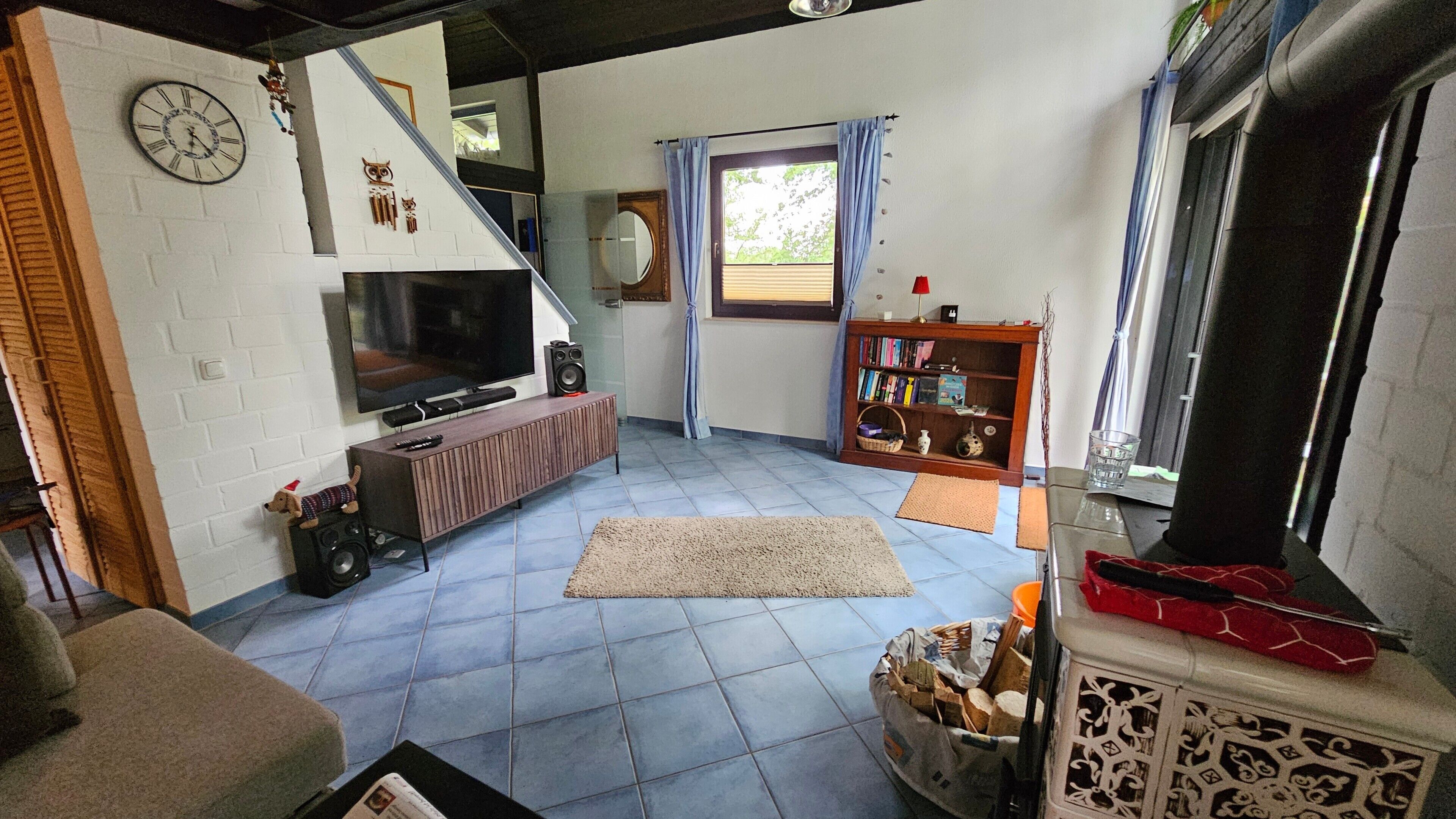 Ein Wohnzimmer mit Fernseher, Lautsprechern, Bücherregal, Kamin und einer Treppe.