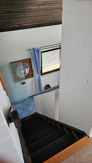 A staircase leading to a room with a window, a mirror, and a door.