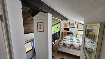 Ein Schlafzimmer mit Bett, Schreibtisch, Stuhl und Fenster.