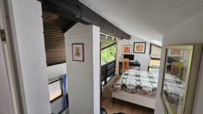 A bedroom with a bed, a desk, a chair, and a window.