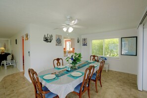 A dining area with a table set for four, surrounded by wooden chairs with blue cushions.