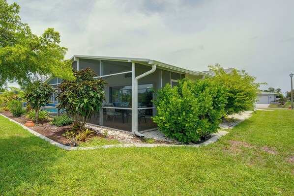 A modern building with a glass enclosure, surrounded by well-maintained grass and various shrubs.