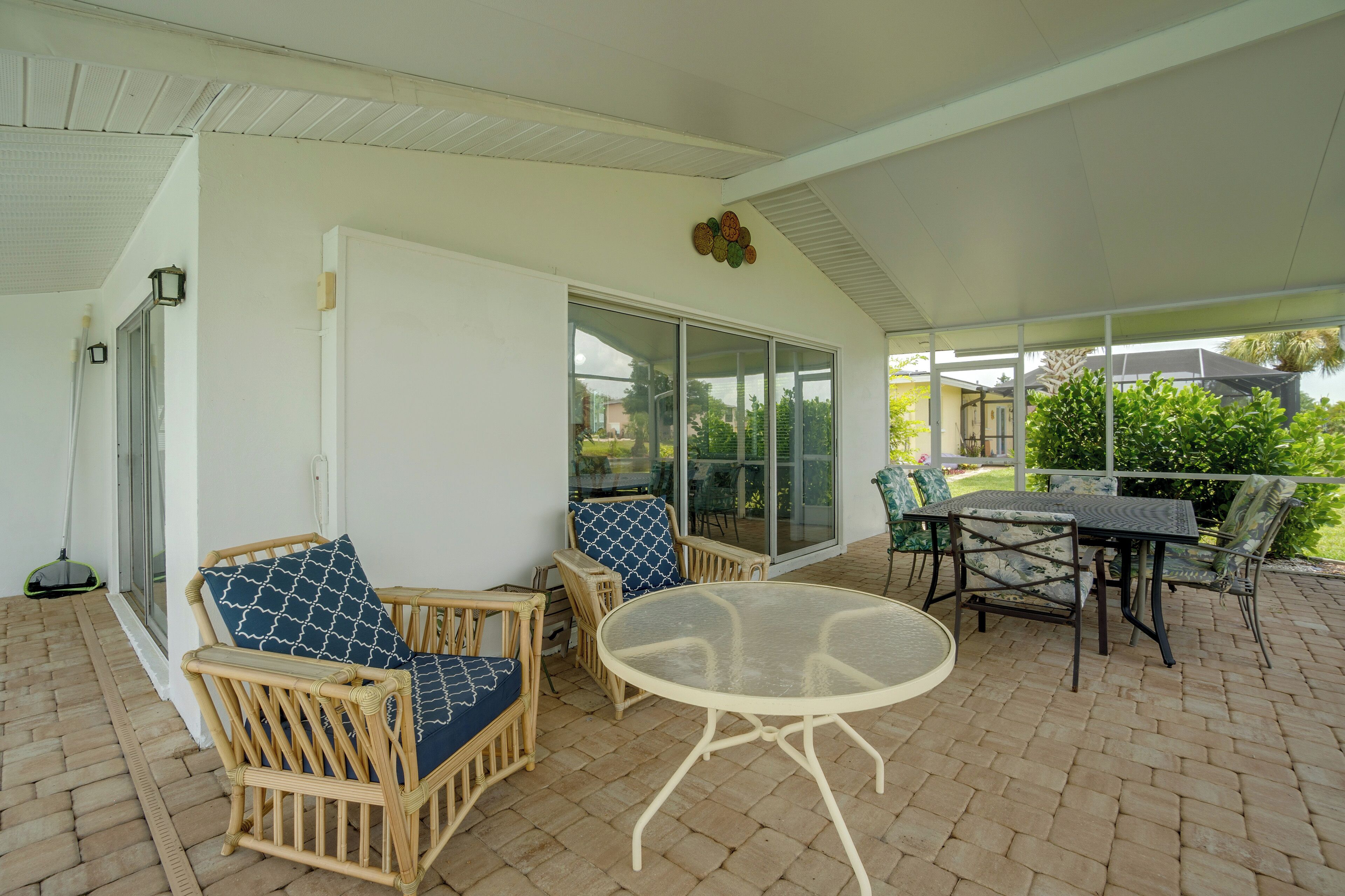 Un patio cubierto con mobiliario de mimbre y una mesa de vidrio.