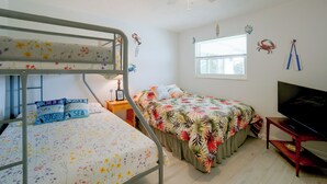 Ein Schlafzimmer mit Etagenbetten, einem Einzelbett, einem Fernseher und dekorativen Wandstickern.