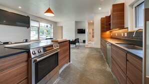 Eine moderne Küche mit Holzschränken, einem eingebauten Ofen und einer großen Kochinsel mit Spüle.