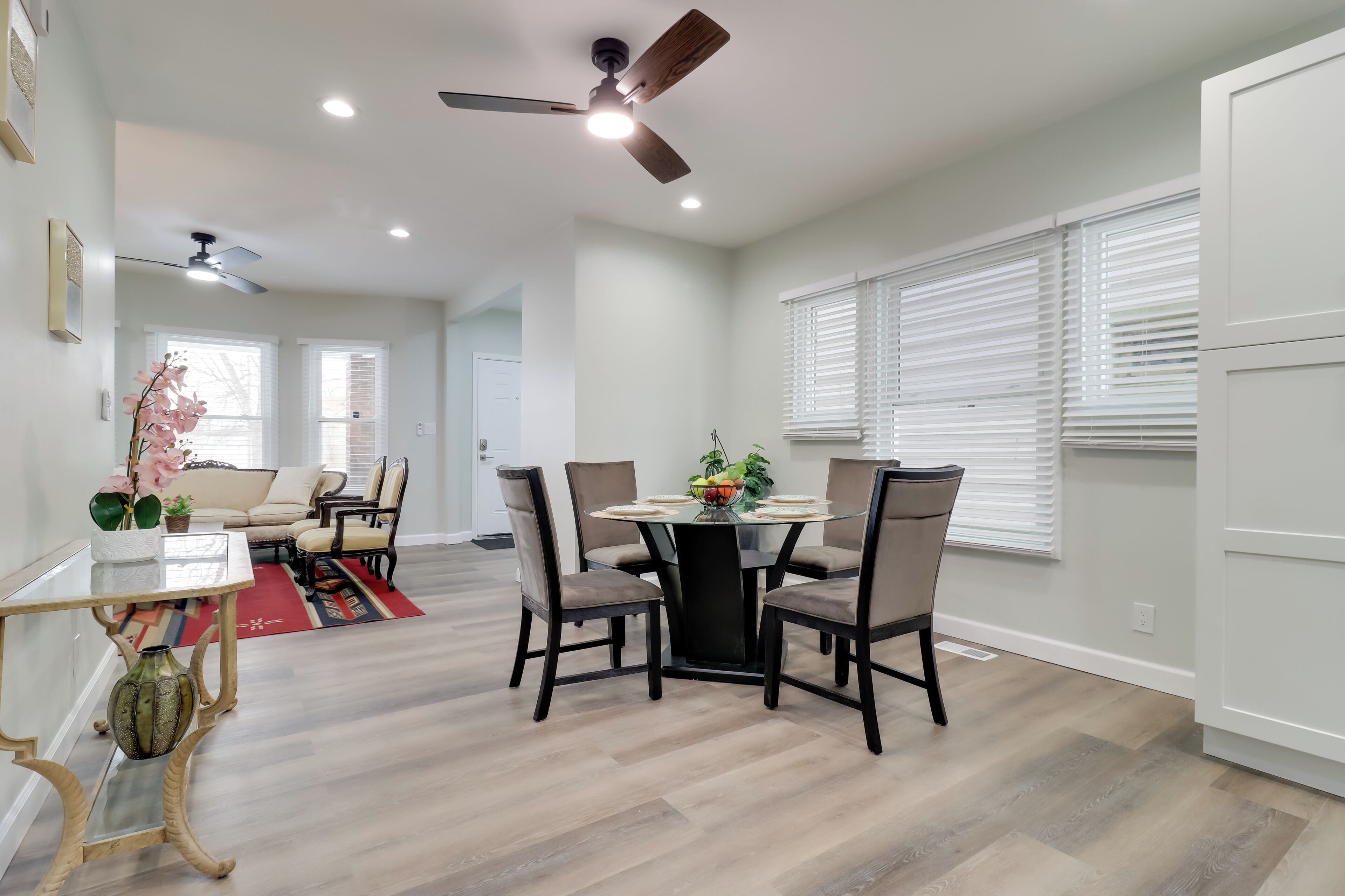 Un espace repas moderne avec une table ronde, quatre chaises et un ventilateur de plafond.