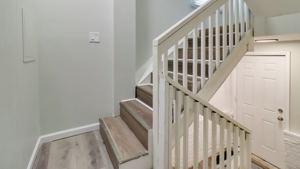 Eine Treppe mit weißen Geländern und Holzstufen, die zu einer weißen Tür führt.