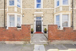A two-story brick building with a sign reading 'WARDEN HOUSE' above the entrance. - Sunset Views - North East Escapes (Tynemouth)