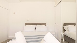 A hotel room with a bed, a bedside table, a mirror, and a wardrobe. - Sunset Views - North East Escapes (Tynemouth)